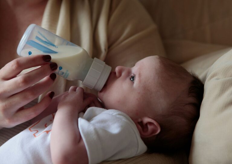 baby drinking from a bottle in mother's arms