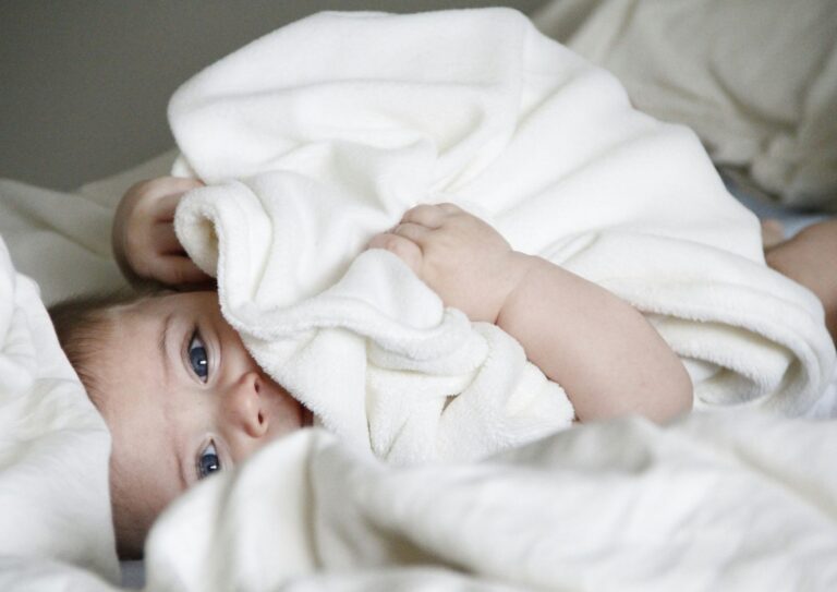 baby laying down in bed cozy with a blanket